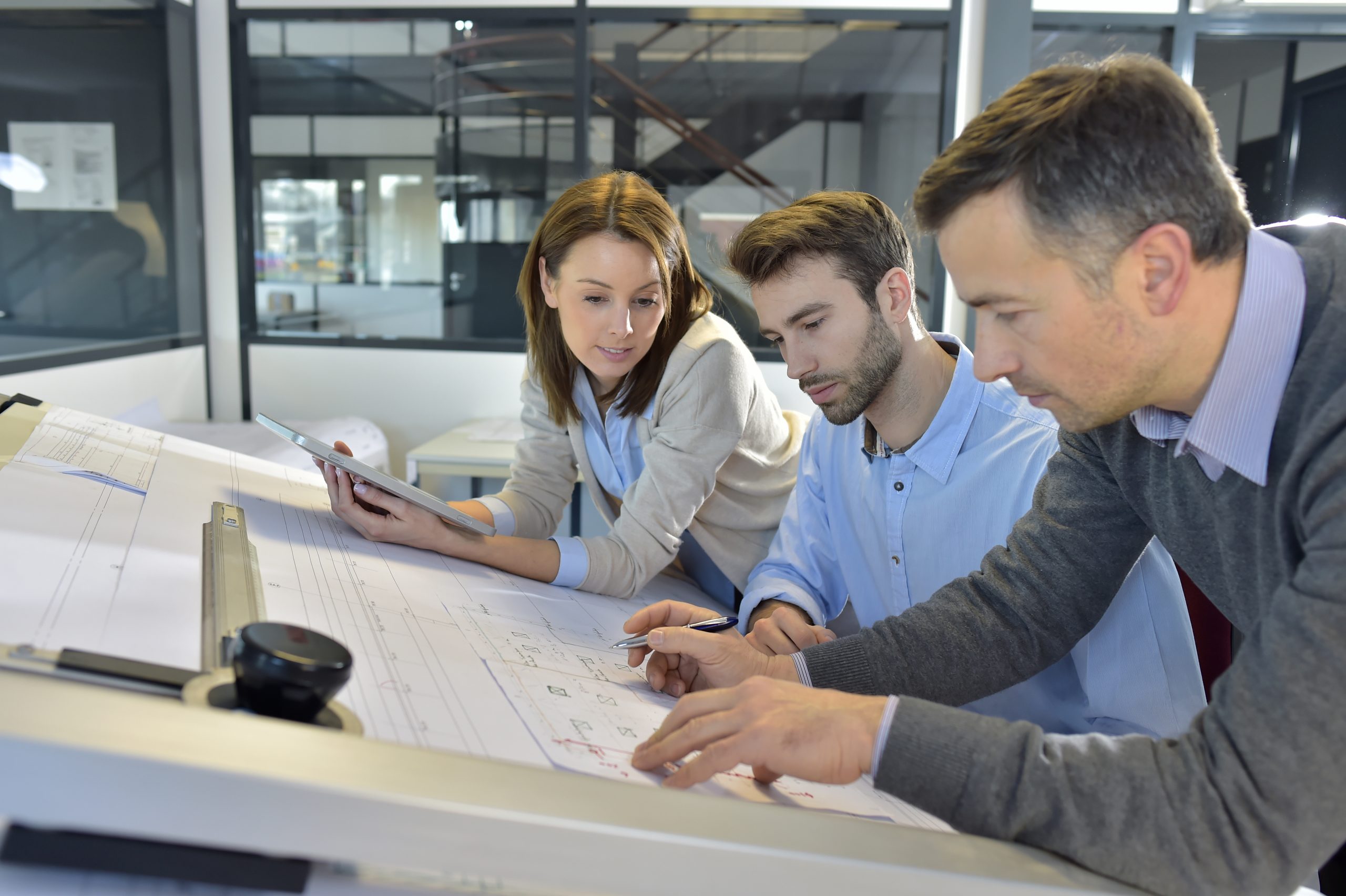 A group of people in an office, analyzing blueprints for commercial flooring systems.