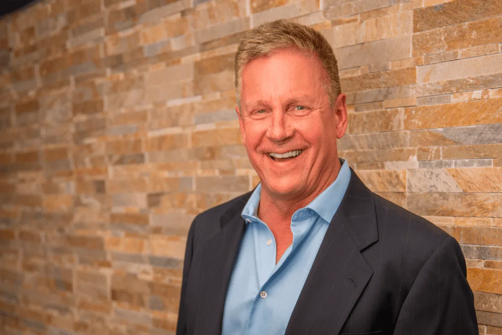 A commercial flooring contractor smiling in front of a brick wall.