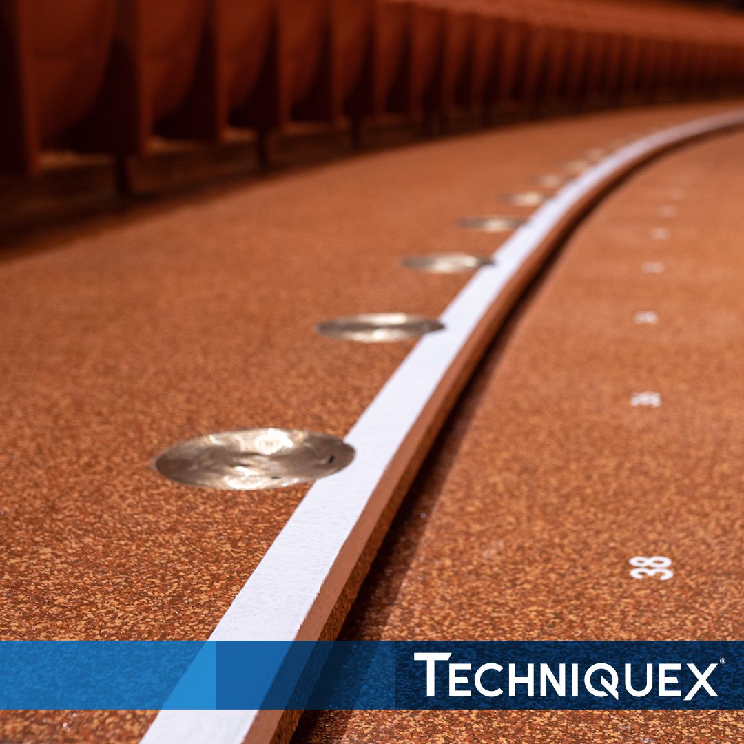 Close-up of a running track lane with metallic markers, numbered section, and a white border, featuring the TechniqueX logo at the bottom.