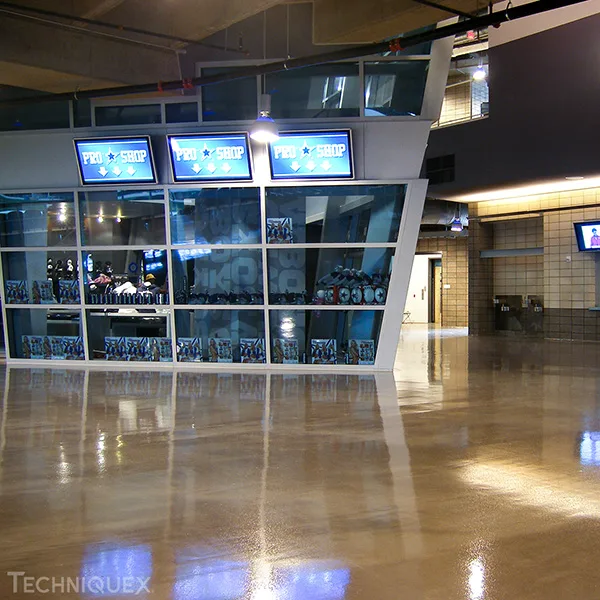 A modern sports pro shop with large glass windows and digital signs, displaying merchandise inside a brightly lit, polished lobby area.