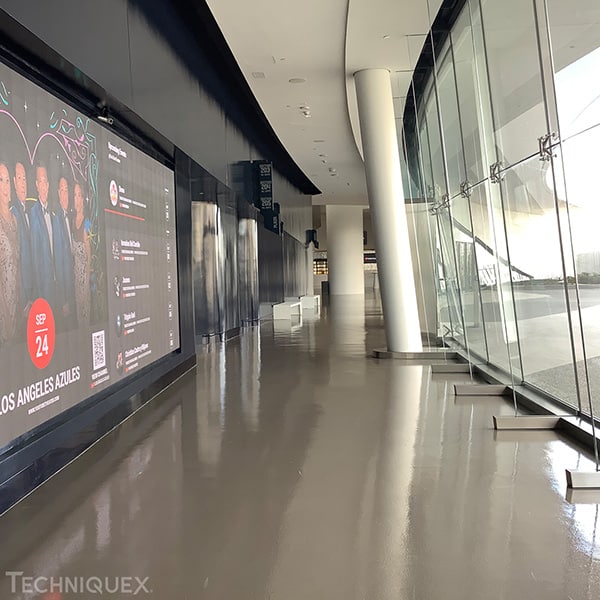 Modern hallway with a shiny floor, glass wall on the right, and a digital event advertisement for September 24 on the left side.