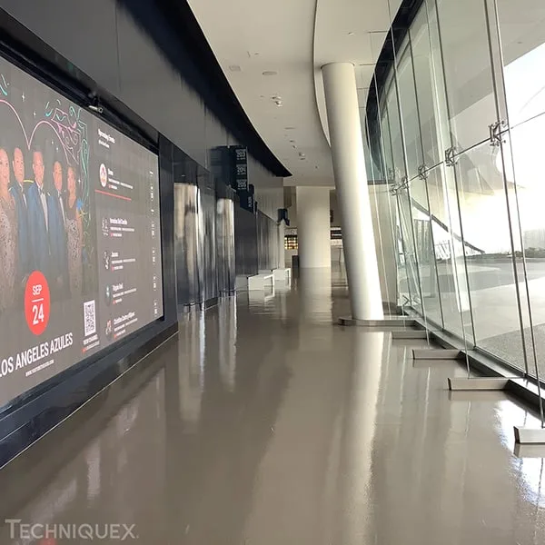Modern hallway with a shiny floor, glass wall on the right, and a digital event advertisement for September 24 on the left side.