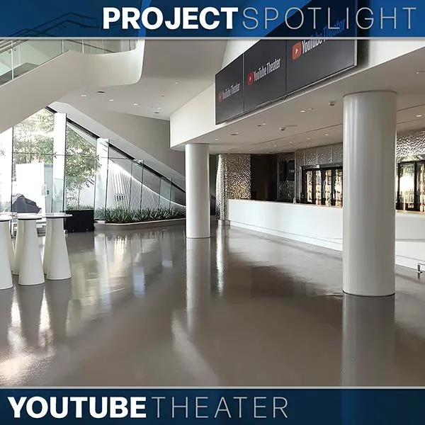 Spacious lobby of YouTube Theater with polished floors, white columns, glass walls, and a counter under digital signs.