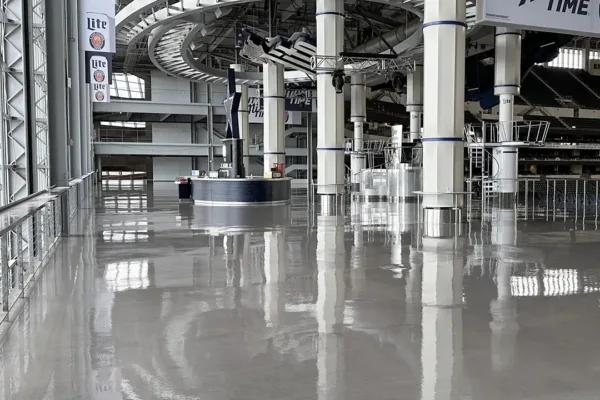 Interior view of a large stadium concourse with polished floors, support columns, and Miller Lite signage.