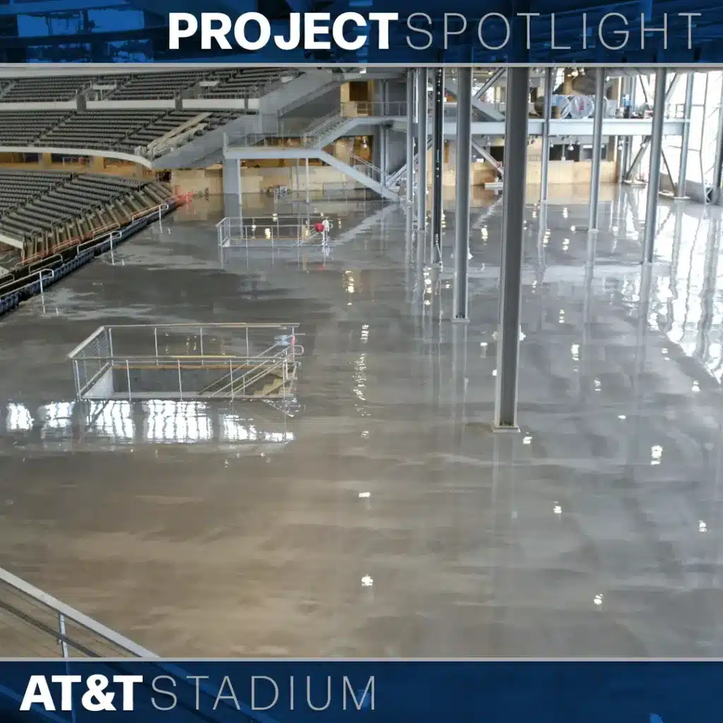 A polished, reflective concrete floor inside AT&T Stadium with stadium seating and staircases visible.