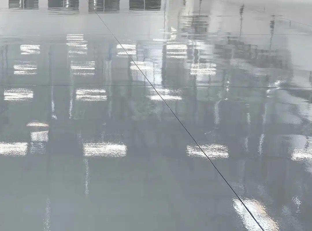 A high-gloss gray concrete floor showing the reflective quality often compared between polyaspartic vs epoxy finishes.